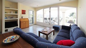 A living room with a sofa, a coffee table, and a TV. There is a bookshelf and a door leading outside. - Vacation home Bilbao by Interhome (Roses)