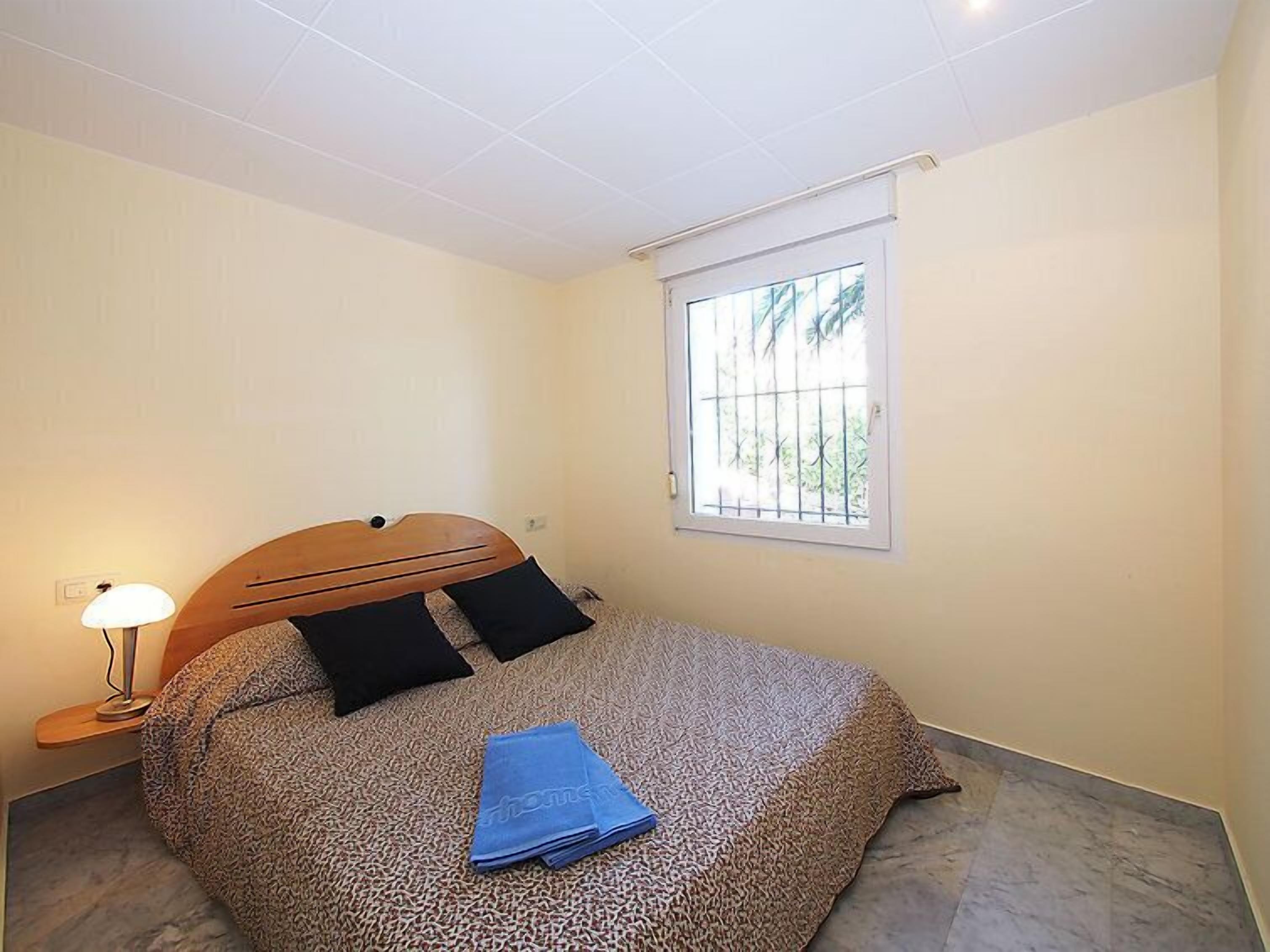 Une chambre à coucher avec un lit, une fenêtre et une lampe.