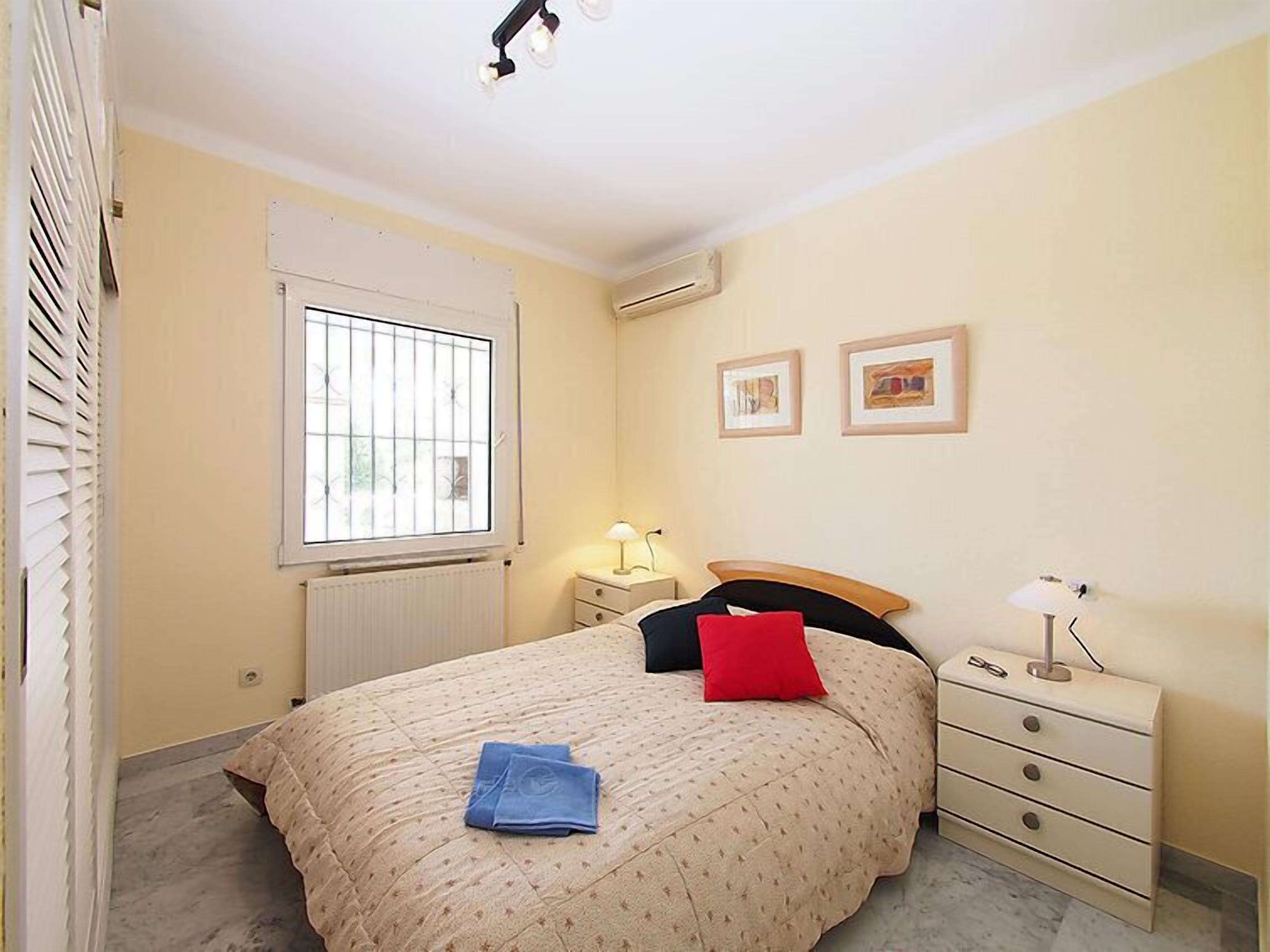 A bedroom with a bed, bedside tables, a window, and wall-mounted artwork.