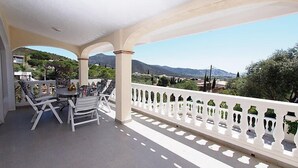 A covered outdoor seating area with a view of mountains and greenery. - Vacation home Bilbao by Interhome (Roses)