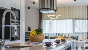 A modern kitchen with a central island, stainless steel appliances, and a hanging light fixture.