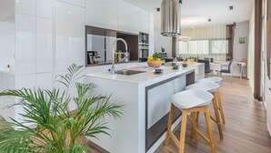 A modern kitchen with a central island, stainless steel appliances, and a large window.