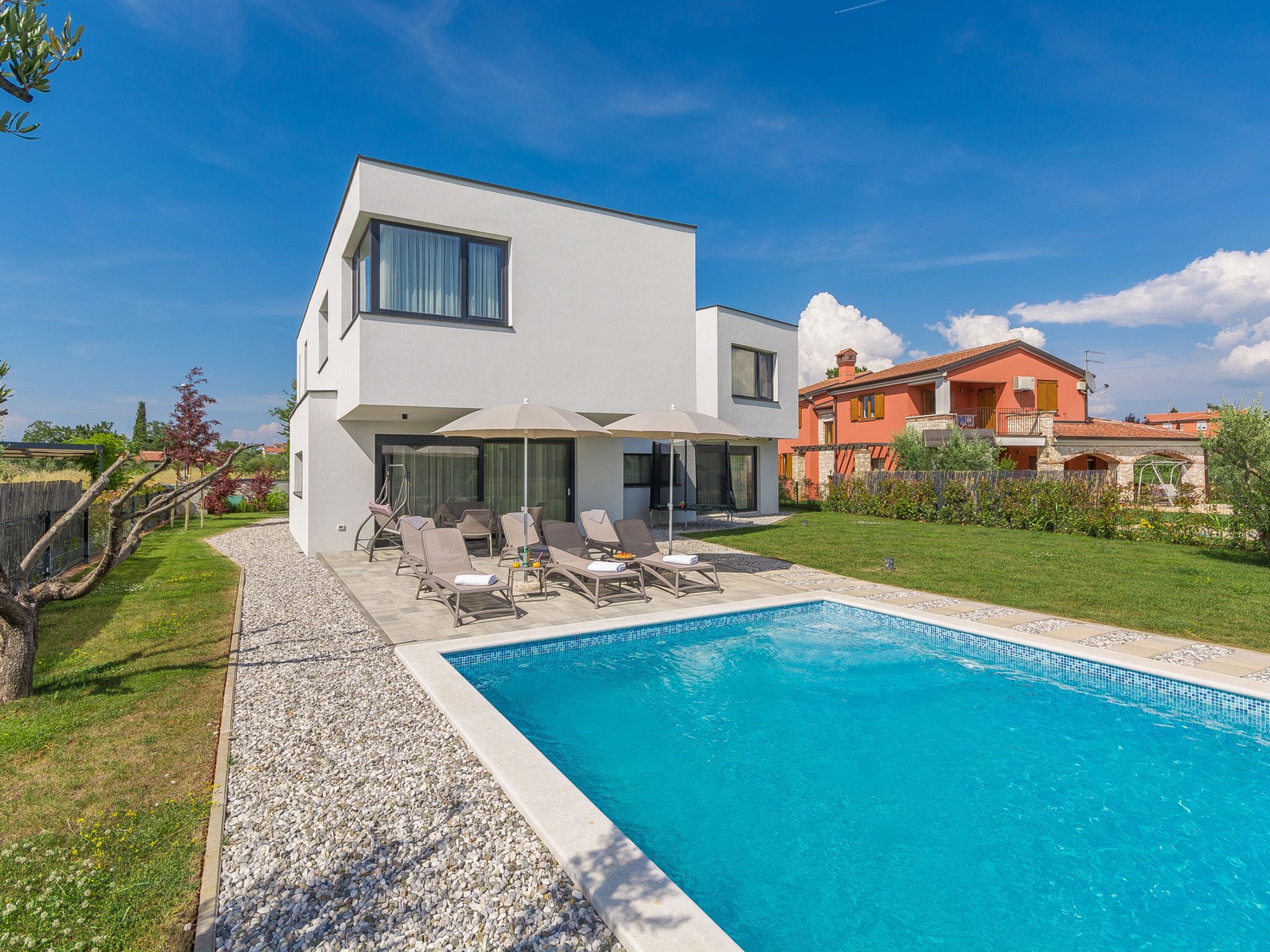 Une maison moderne à deux étages, dotée d’une piscine, d’un espace extérieur aménagé et d’un jardin bien entretenu.