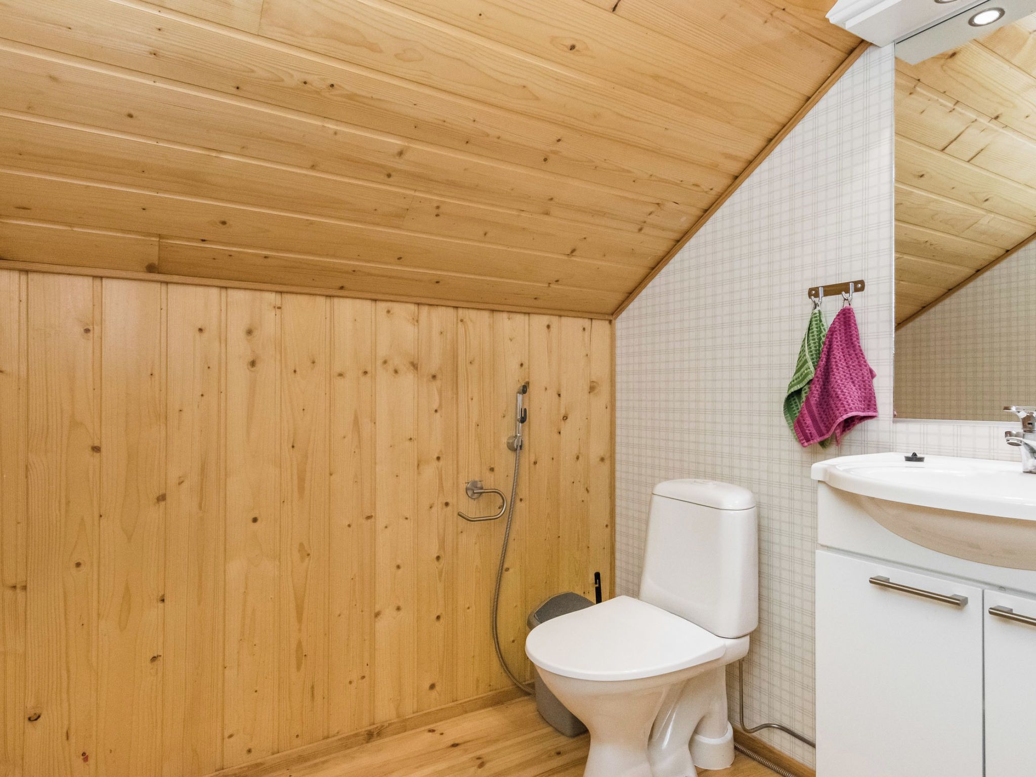 Un baño con paneles de madera, un inodoro, un lavamanos y una ducha.