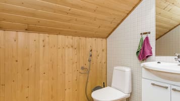 Un baño con paneles de madera, un inodoro, un lavamanos y una ducha.