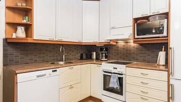 A compact kitchen with white cabinets, a built-in microwave, a stove, and a dishwasher.