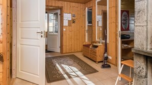 Een houten interieur met een deur, een spiegel, een stofzuiger en een stenen openhaard.