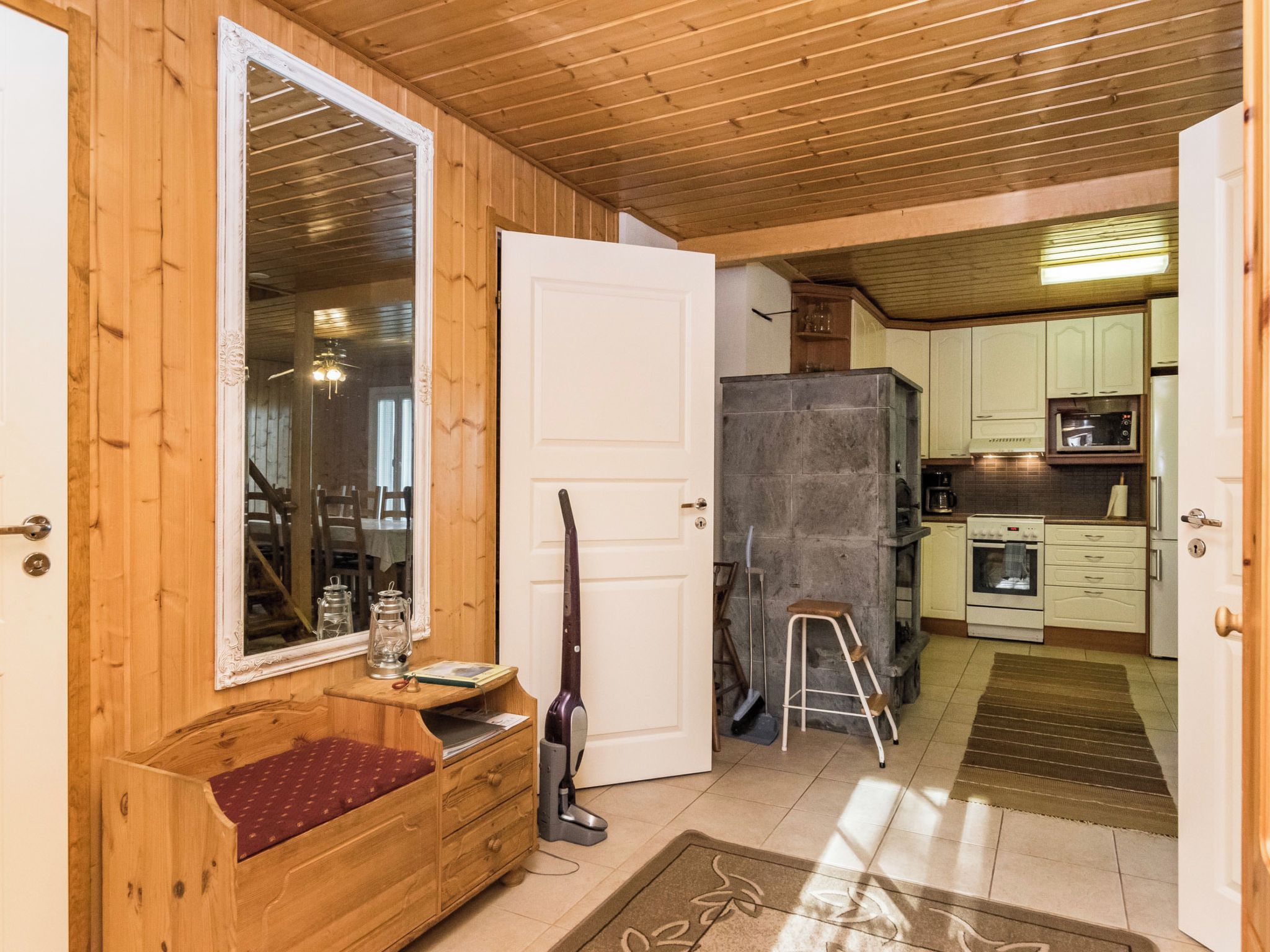 Un interior de madera con un banco, una puerta, una zona de cocina con armarios y electrodomésticos.