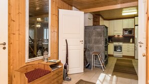 Een houten interieur met een deur naar een keuken, een bank met een kussen en een stofzuiger.