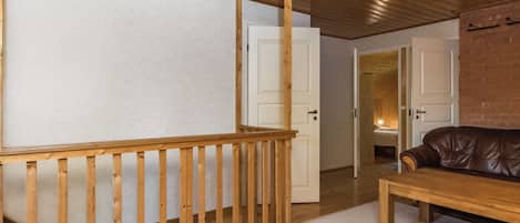 Una scala in legno con ringhiera, un divano in pelle e una porta bianca che conduce in un'altra stanza.