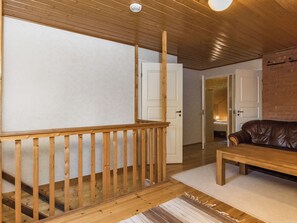 Un escalier en bois avec une rampe, un canapé en cuir et une porte blanche donnant sur une autre pièce.