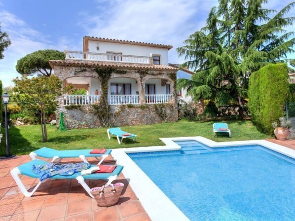 A pool area with lounge chairs and a stone wall.