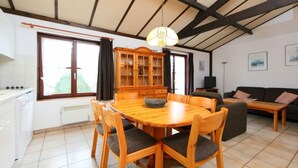 Een ruime woonruimte met een houten eettafel, stoelen, een bank en een kast.