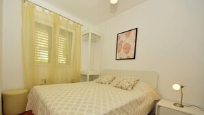 A bedroom with a bed, bedside table, and a nightstand.