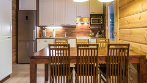 A compact kitchen with wooden cabinets, a refrigerator, a microwave, and a dining table with chairs. - Rentotahko by Interhome (Nilsiä)