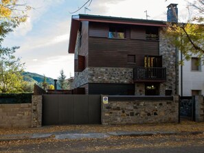 A two-story house with a stone facade, a balcony, and a gated entrance.