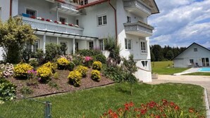 A two-story building with a balcony, surrounded by a well-maintained garden with various flowers and shrubs. - Apartment Frank by Interhome (Feldkirchen in Kärnten)