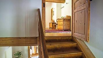 Un escalier en bois mène à une pièce où se trouvent une commode en bois et une petite table.