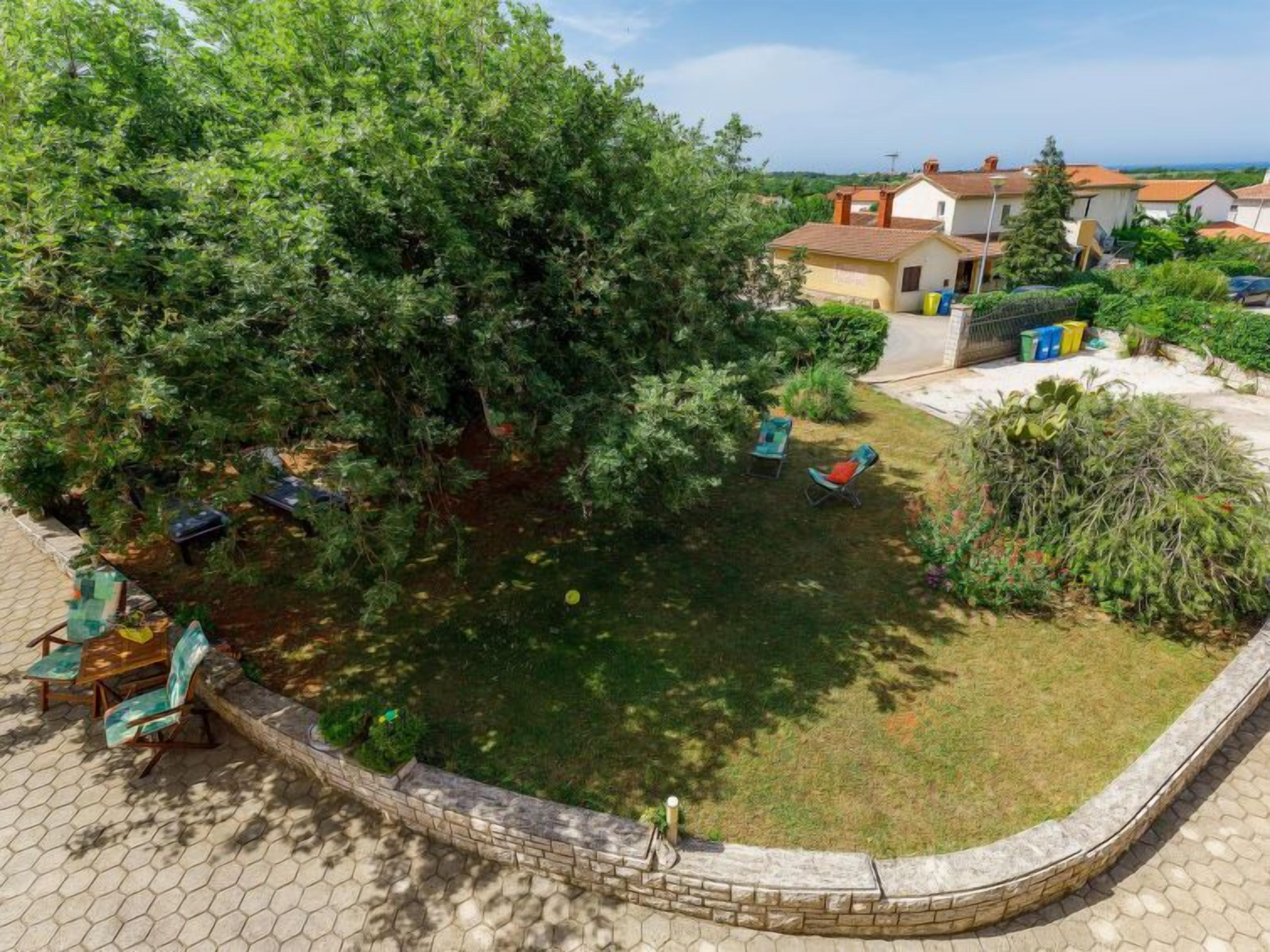 A garden with a pond, seating area, and a view of houses in the background.