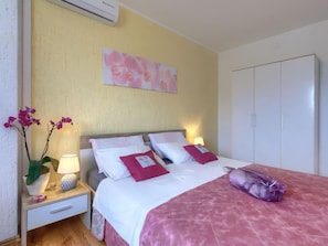 A hotel room with a bed, nightstands, a lamp, a wardrobe, and a wall-mounted air conditioner.