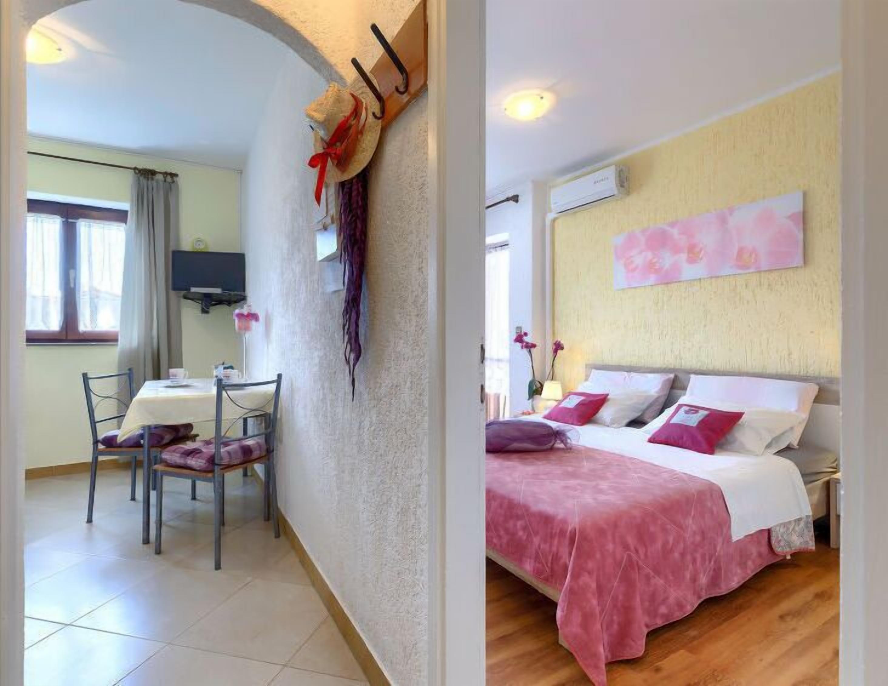 A room with a bed, a dining area with a table and chairs, and a wall-mounted TV.