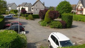 Zona residencial con casas, coches aparcados y setos cuidados.