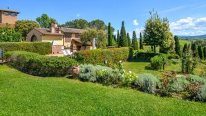 Una villa con jardín, piscina y vistas al campo.