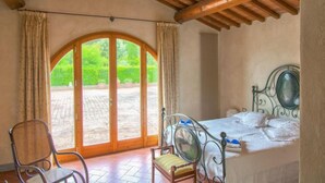 Un dormitorio con cama, una silla y un amplio ventanal de arco.