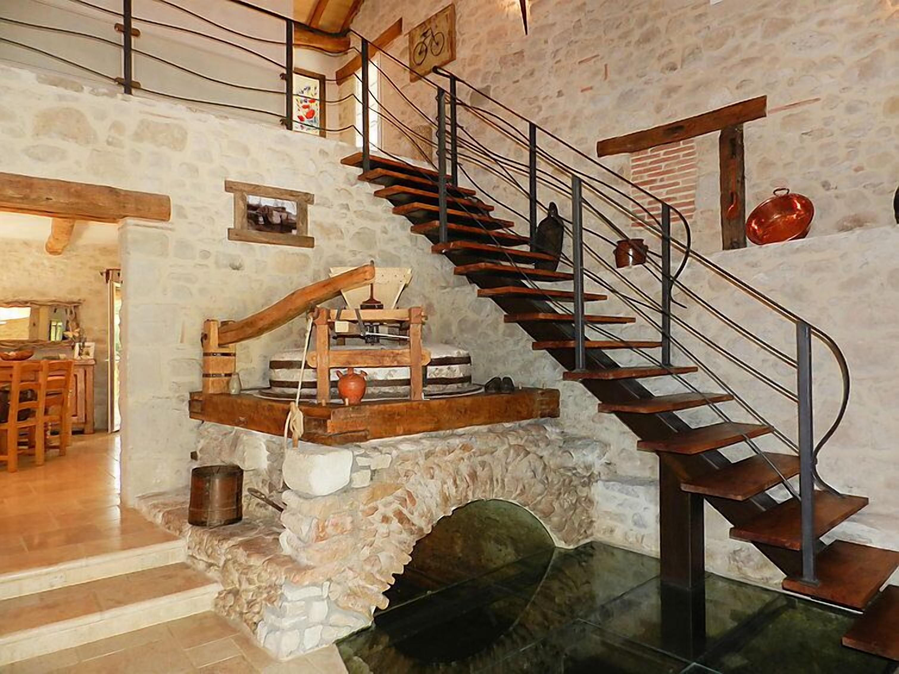 Una escalera de piedra rústica con barandilla de metal que conduce a una puerta de madera.