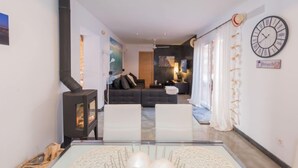 Ein modernes Wohnzimmer mit Kamin, einer Sofagarnitur und einem Essbereich mit Glastisch.