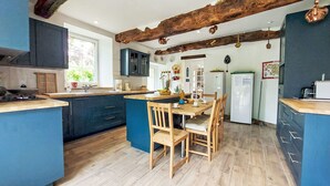 A modern kitchen with blue cabinets, a wooden dining table, and a rustic ceiling beam.