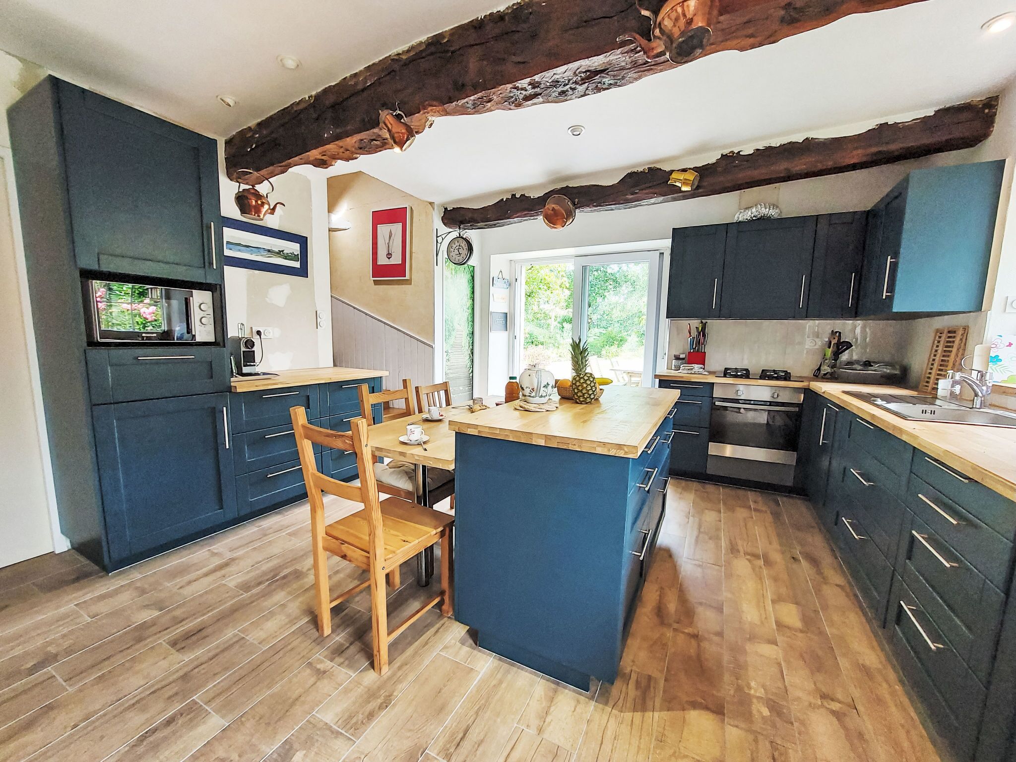 A modern kitchen with dark blue cabinets, a wooden dining table, and a large island.