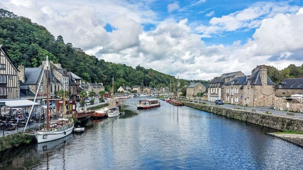 A riverside town with historic buildings, a marina with boats, and a café by the water.