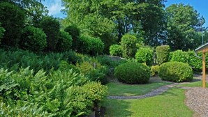 Un jardin bien entretenu, agrémenté de divers arbustes et doté d’un chemin de gravier.