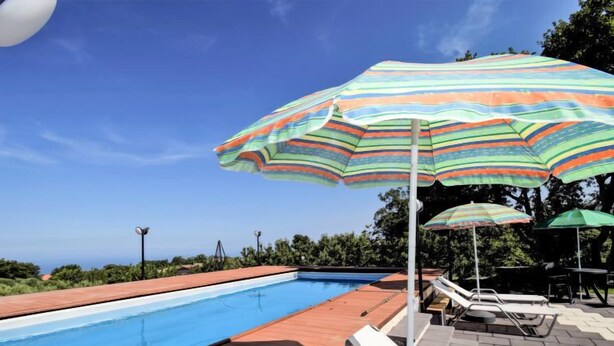 A swimming pool with lounge chairs and striped umbrellas.