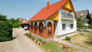 A two-story house with a red-tiled roof, a balcony on the upper floor, and a paved driveway. - Apartment Swing by Interhome (Balatonszarszo)
