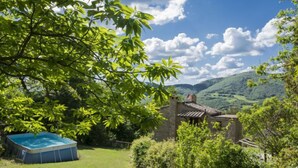 Une maison de campagne avec une piscine, située dans un paysage verdoyant et luxuriant.