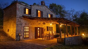 Une maison en pierre dotée d’un patio couvert et d’un espace extérieur aménagé pour s’asseoir.