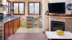 A kitchen with a TV, fireplace, and dining area with a view. - Villa Laura by Interhome (Nerja)