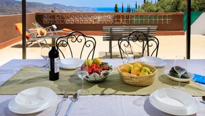 A table set for two with a bottle of wine, glasses, and a fruit bowl on a terrace with a view of the sea and mountains. - Villa Laura by Interhome (Nerja)
