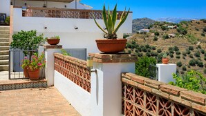 A white building with terracotta pots on the balcony, a brick wall, and a view of a hilly landscape. - Villa Laura by Interhome (Nerja)