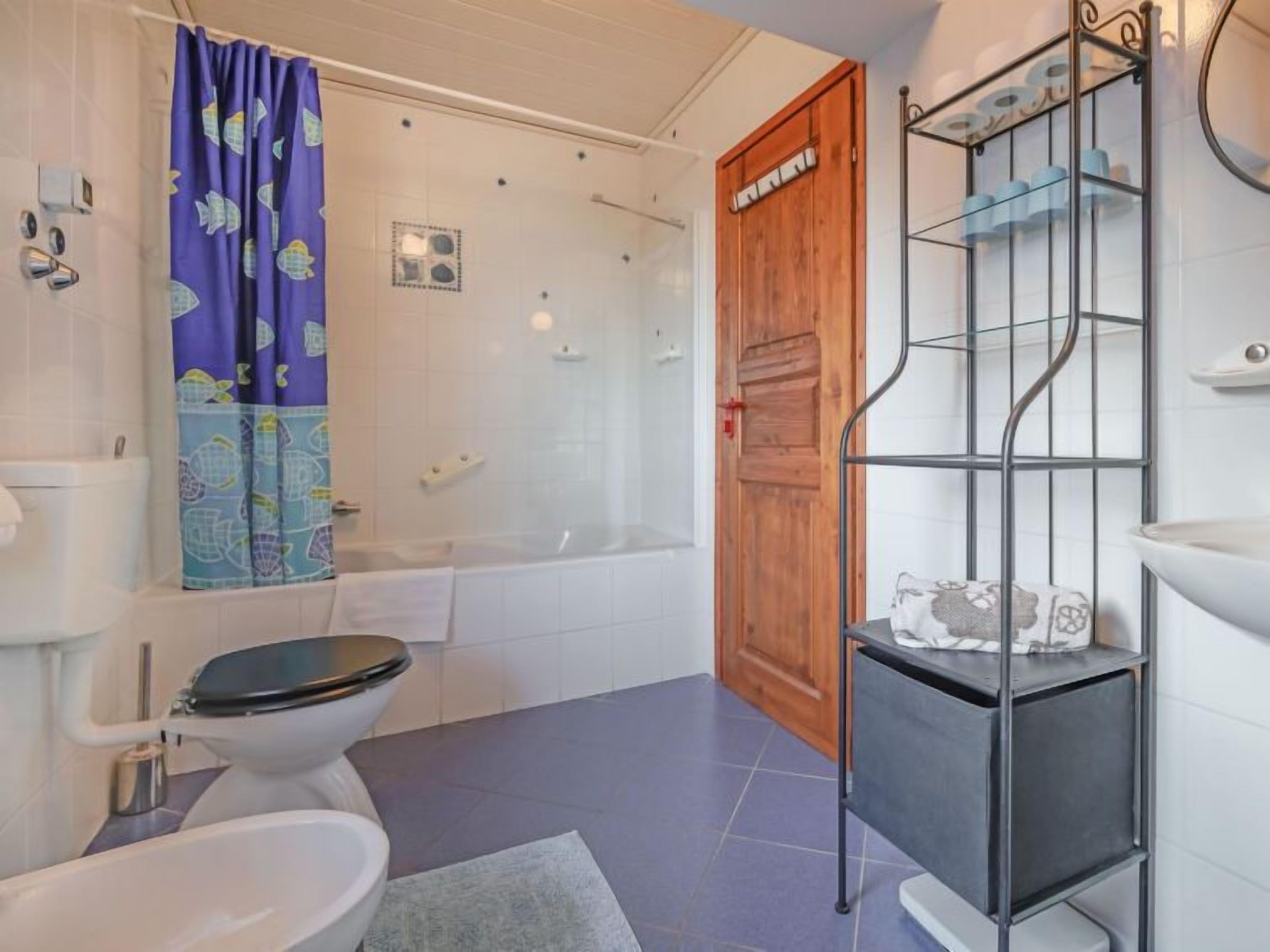 Une salle de bain équipée de toilettes, d’une baignoire, d’une douche et d’une porte en bois.