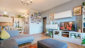 Una sala de estar moderna con sofá, reposapiés y mueble de entretenimiento.