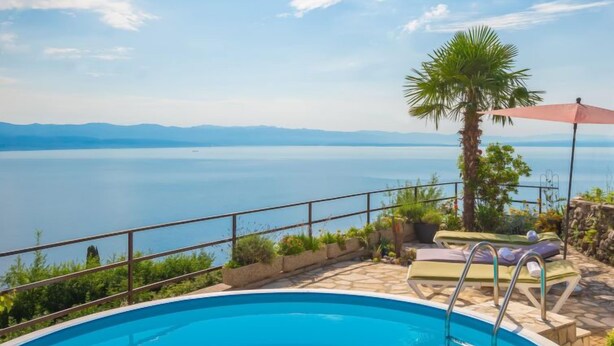 Una piscina con vistas a una gran masa de agua y montañas al fondo.