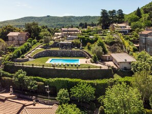 A pool surrounded by stone walls, with a view of a hillside and residential buildings.
