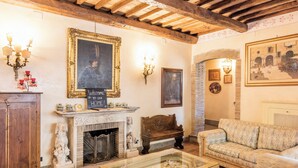 Un salon chaleureux avec une cheminée, un canapé, une table basse et un tableau accroché au mur.