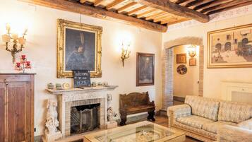 Un salon chaleureux avec une cheminée, un canapé, une table basse et un tableau accroché au mur.