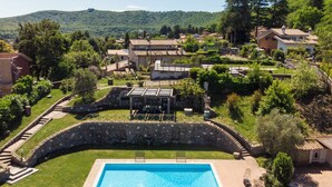 Une piscine avec un pont en pierre, des chaises longues et un mur en pierre.