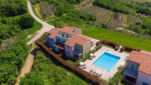 Uma villa com piscina, rodeada por vegetação exuberante e um terreno acidentado.