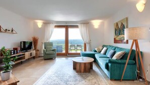 Sala de estar moderna com sofá, mesa de centro, televisão e varanda com vista.